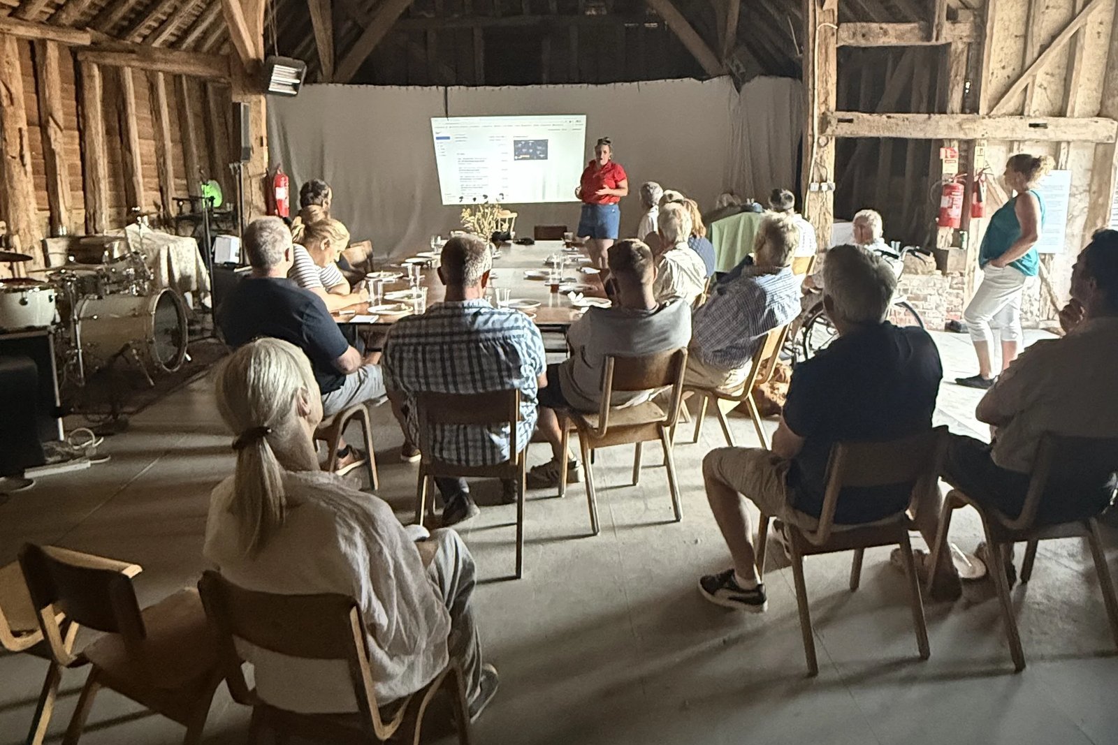 The Hectare Trading team presenting to a seated audience in a barn