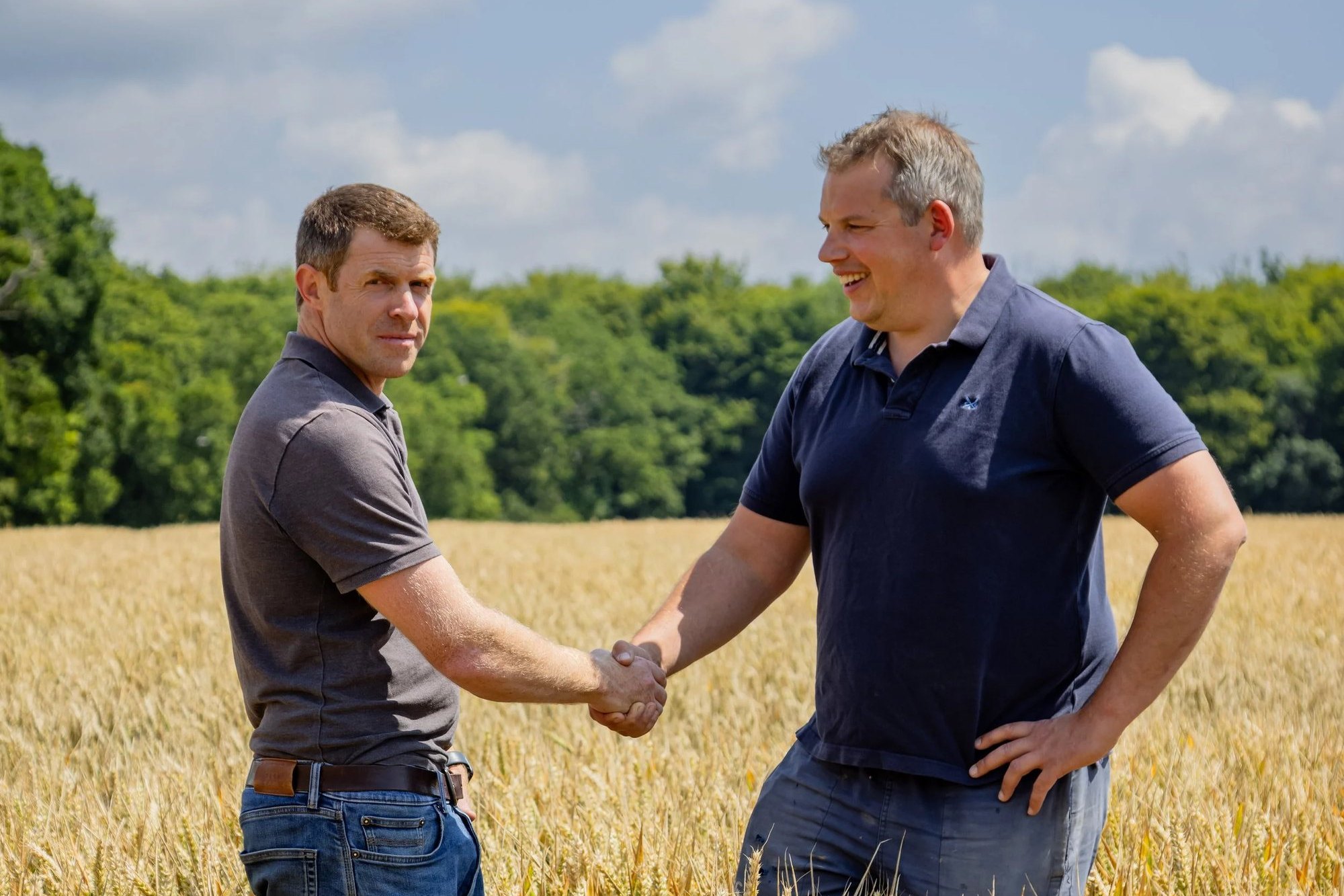 Two farmers shaking hands in a ripe wheat crop